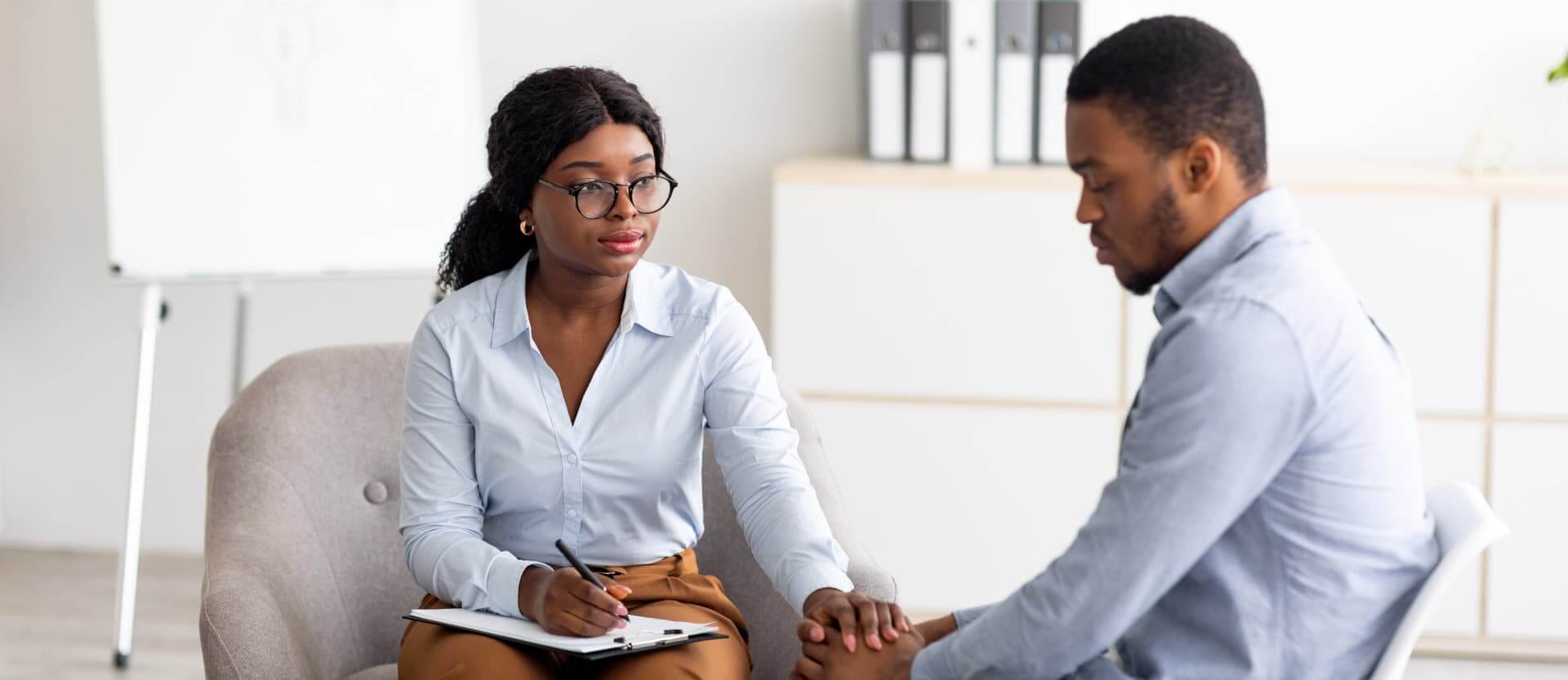 Young psychologist touching male patient hands
