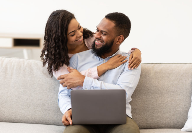 Smiling young black women embracing men from behind