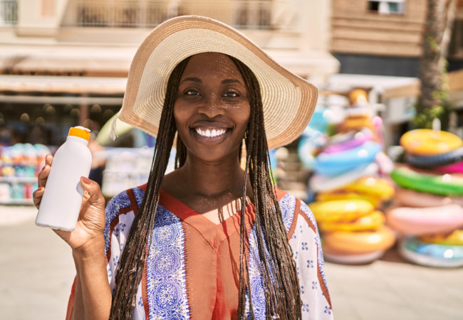 african american woman smiling happy holding sunscreen lotion