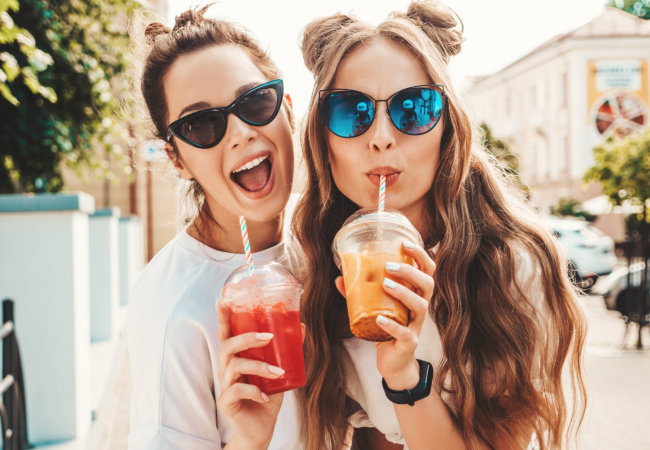 Two young beautiful smiling hipster female in trendy summer clothes