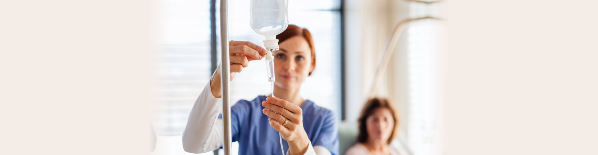 A nurse with IV drip and patient in bed in hospital room