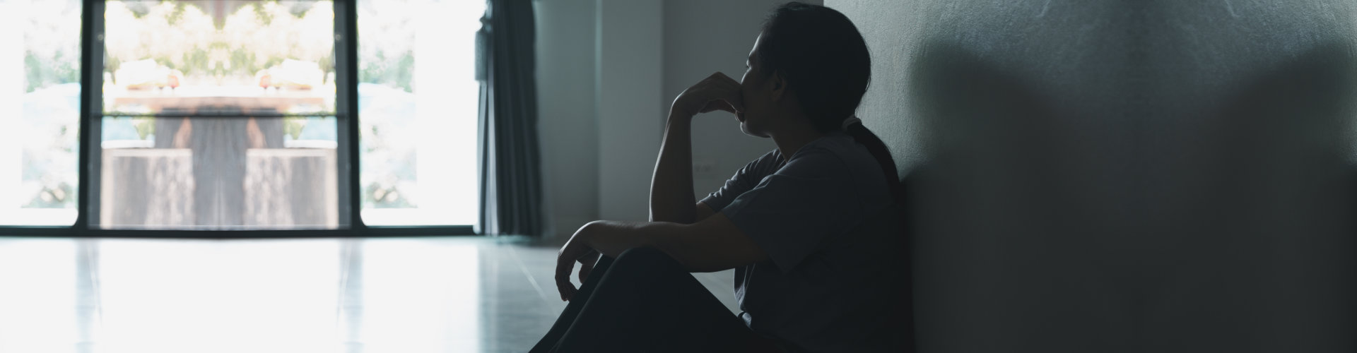 Depressed woman sitting against wall